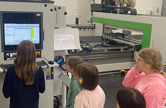 Mehrere Kinder schauen auf den Bildschirm einer CNC-Maschine am nationalen Zukunftstag bei der Zemp AG.
