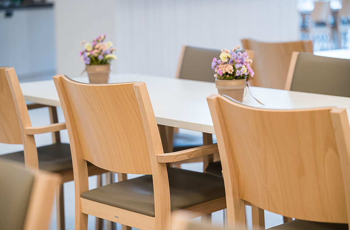 Holzstühle mit grünen Sitzpolster in der Cafeteria des Betagtenzentrums Lindenrain.