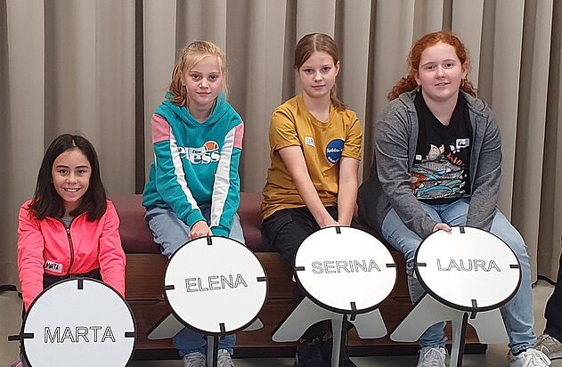 Vier Kinder präsentieren stolz ihren eigenen Holzstuhl am nationalen Zukunftstag bei der Zemp AG.