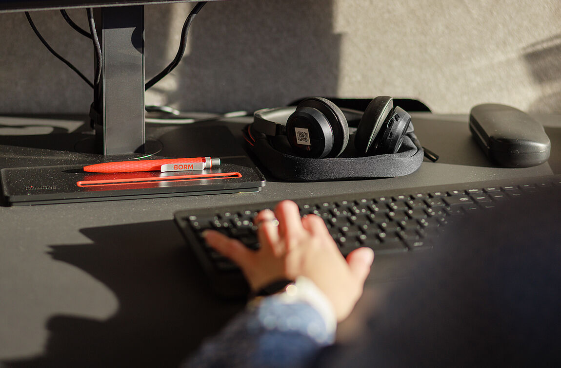 Die Hand einer Mitarbeiterin der Firma Borm auf einer schwarzen Tastatur