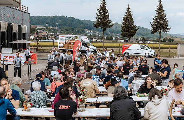Mehrere Festbänke gefüllt mit Personen am Tag der offenen Tür bei der Zemp AG.