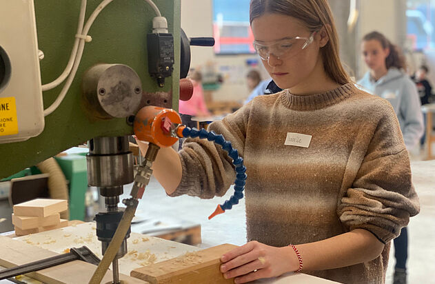 Ein Mädchen bohr ein Lock in ein Holzbein beim nationalen Zukunftstag bei der Zemp AG.